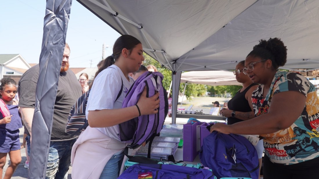 Student receiving a backpack at the Clark Avenue giveaway