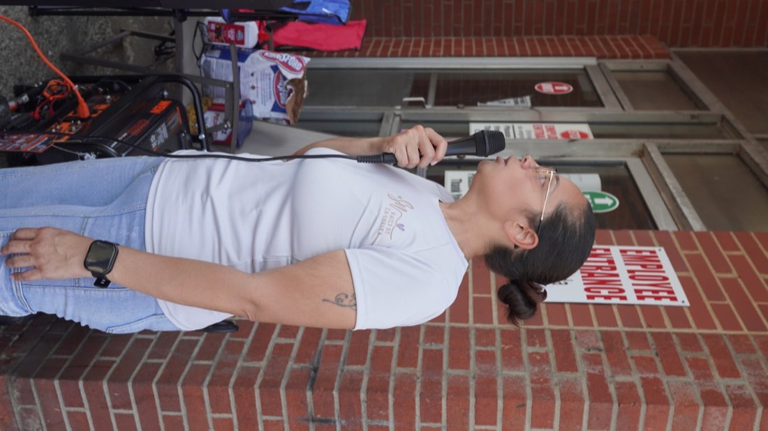 Event organizer speaking into a microphone outside Clark Auto Parts