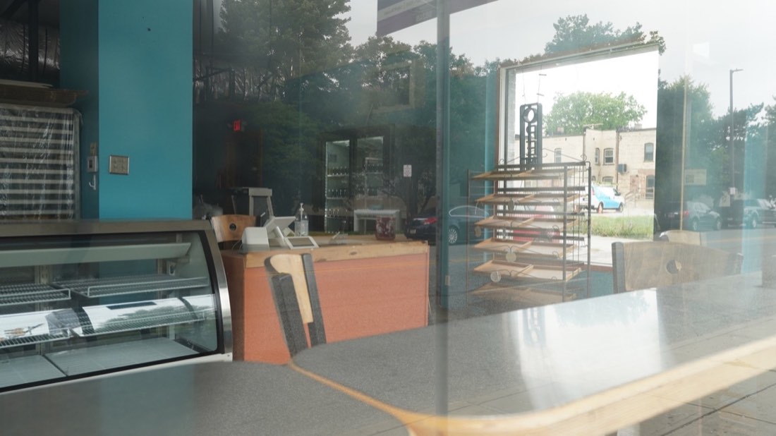 Bakery racks and neighborhood reflections through the storefront window