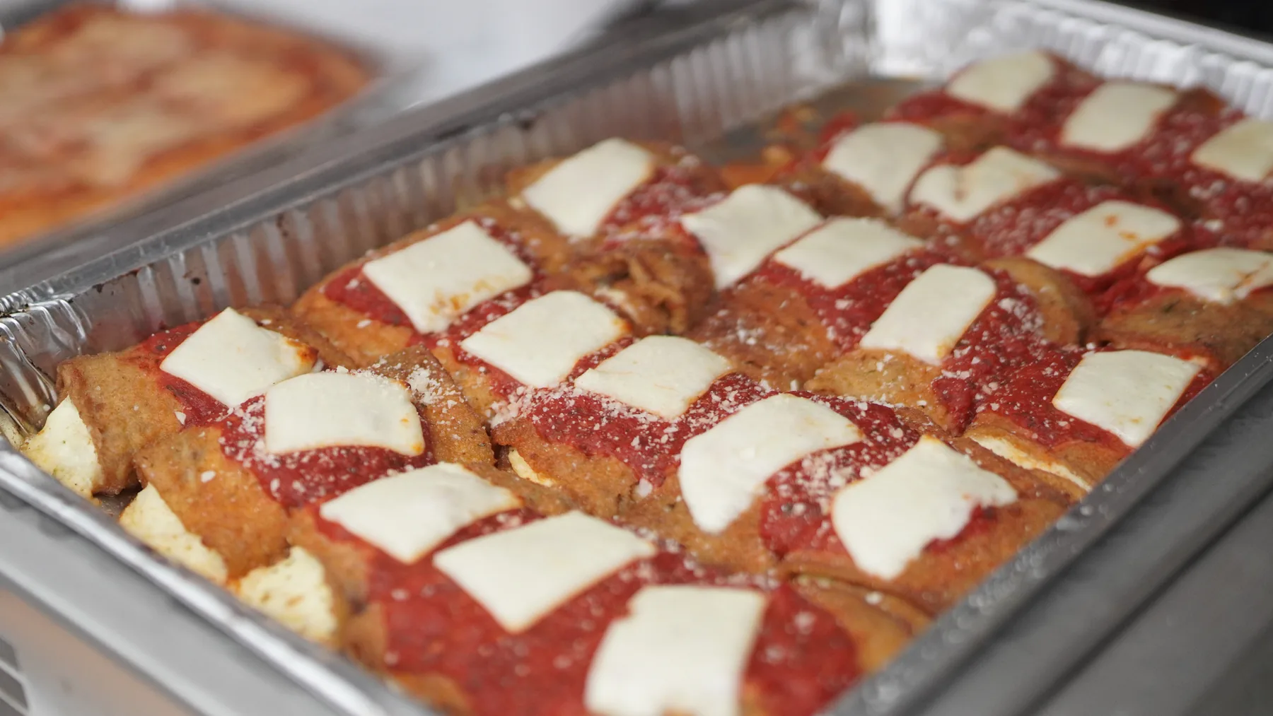 Breaded eggplant with red sauce and cheese is prepared for serving.