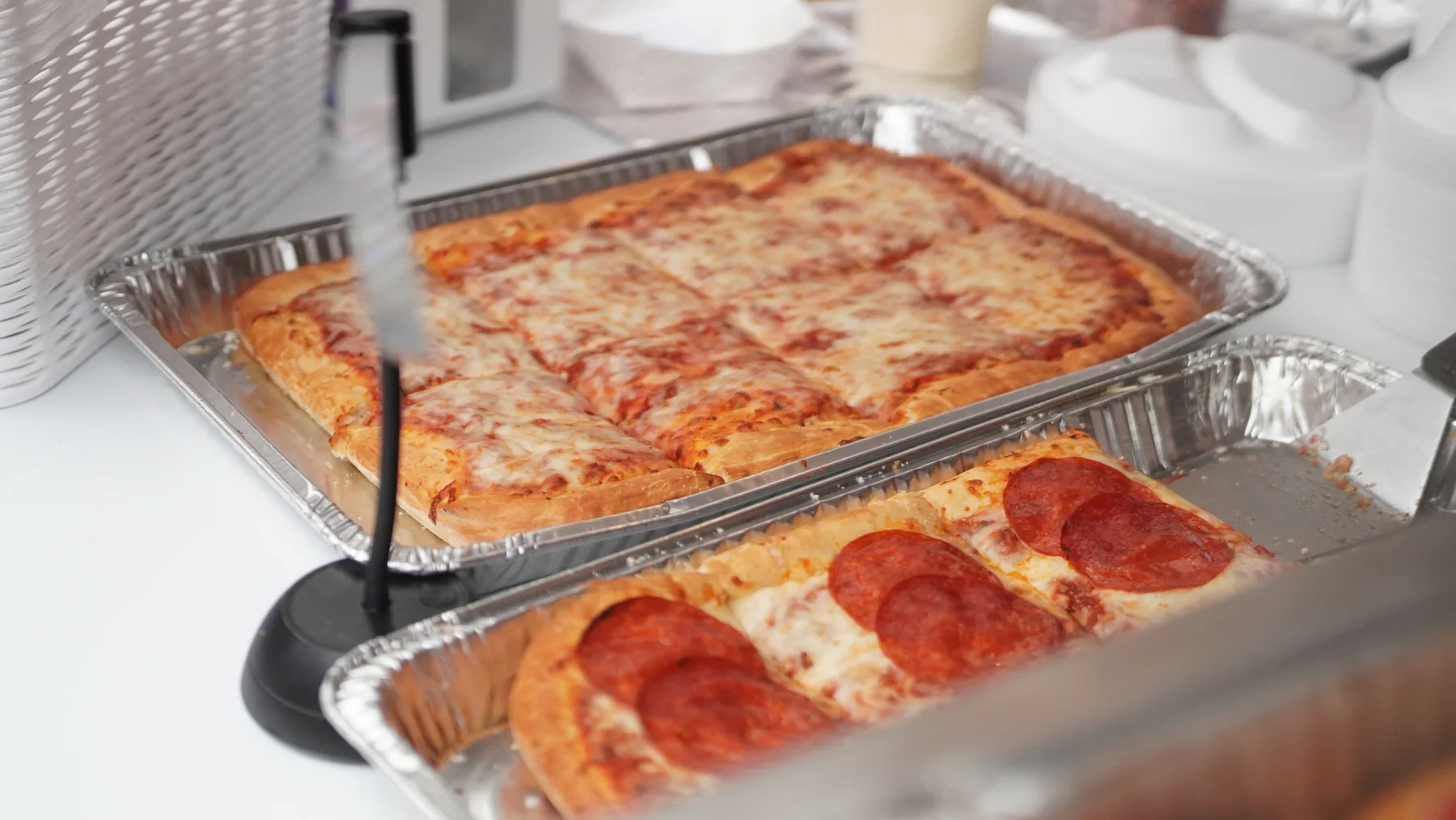 Cheese and pepperoni pizza are served from trays.