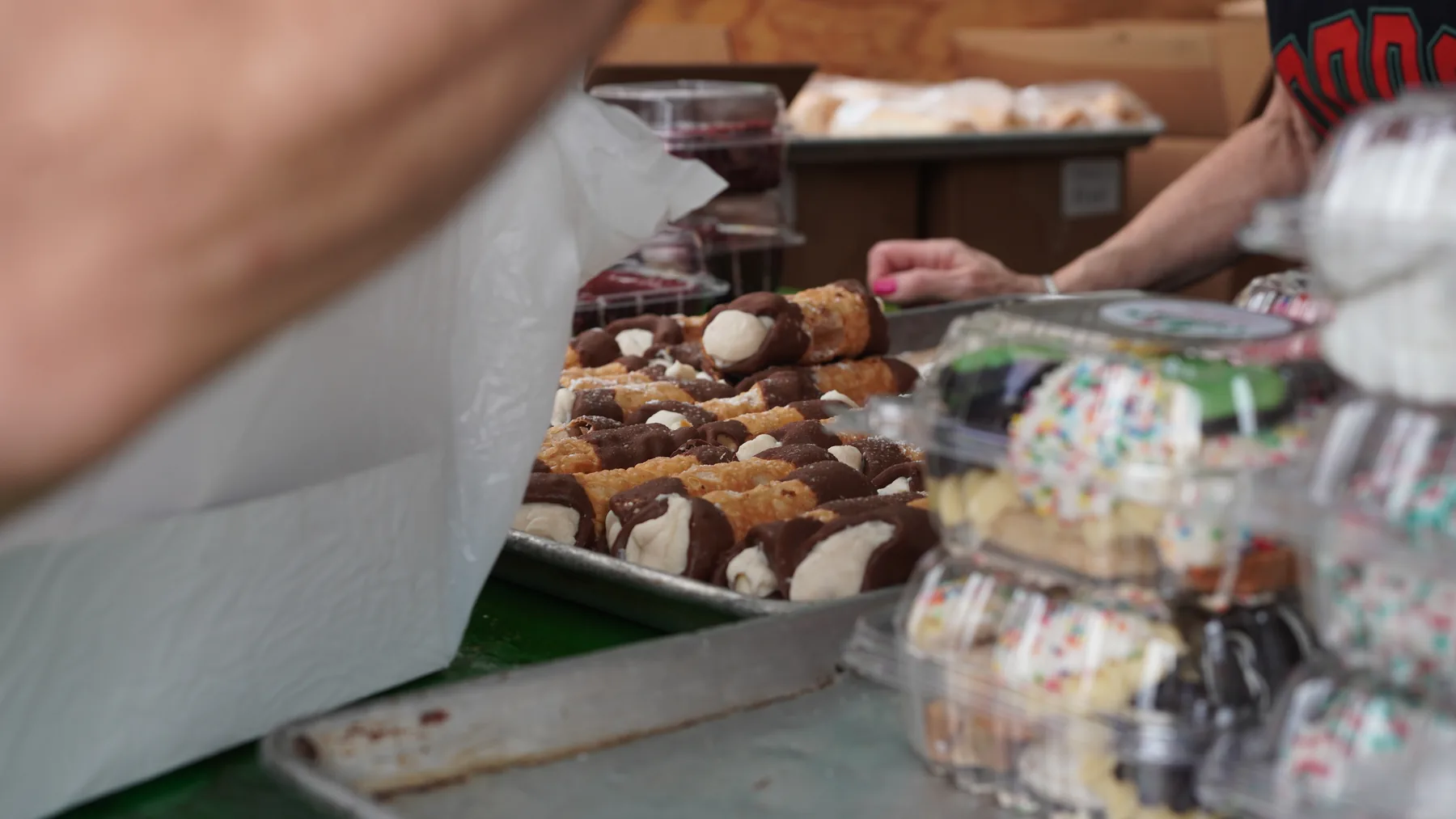 Cannoli and Italian pastries are arranged at a Feast counter.