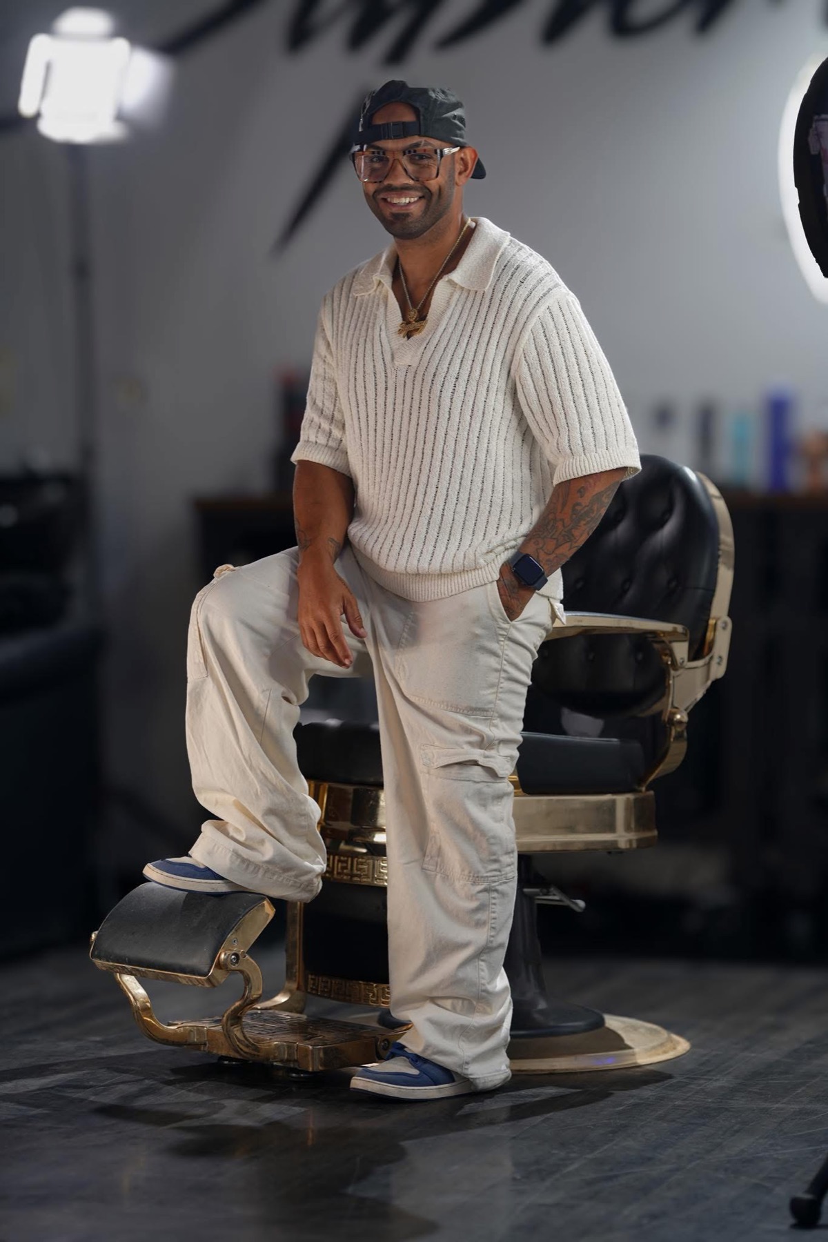 Khristian Santana beside a gold barber chair at Supremacy Barbershop