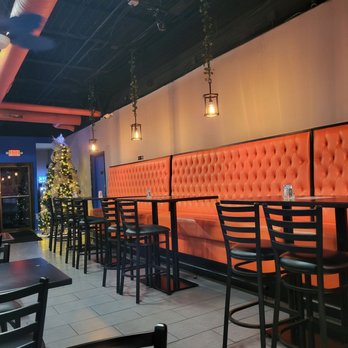 Orange booth seating and high-top tables inside The Blue Palm