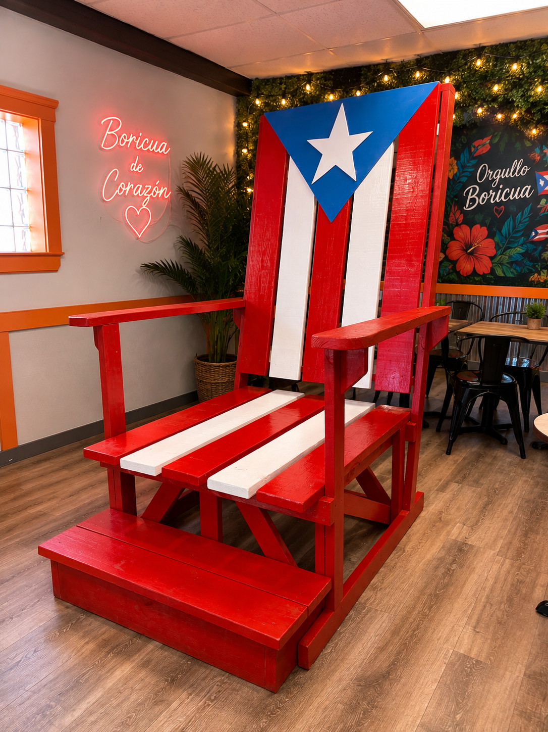 Giant wooden chair painted like the Puerto Rican flag inside a room with Boricua de Corazón and Orgullo Boricua signs.