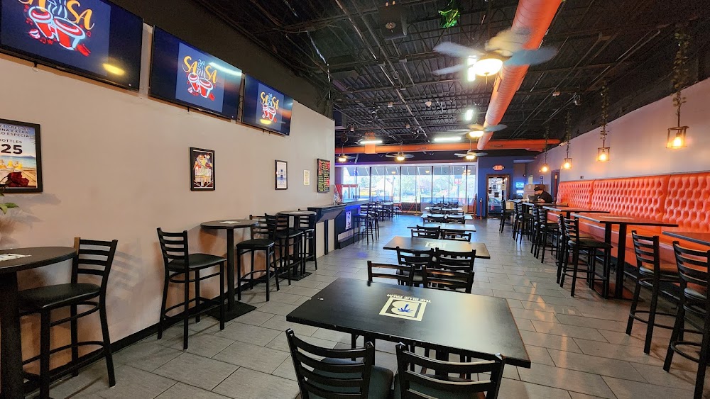 Dining room inside The Blue Palm with tables, orange booth seating and televisions