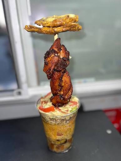 Layered Puerto Rican food cup topped with grilled meat and fried plantains.