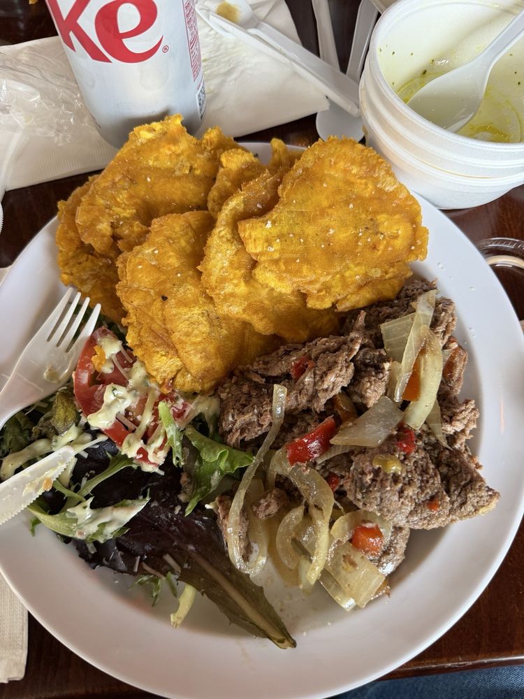 Puerto Rican plate with tostones, seasoned meat, onions and salad at Sazón Boricua