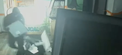 Cropped interior surveillance view of a person holding a rectangular object