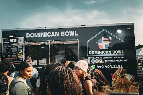 Customers gather at the Dominican Bowl food truck, with its name and Dominican flag logo visible.