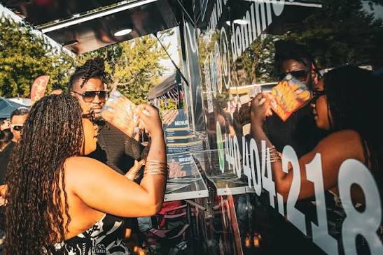 Customers stand next to the reflective side of the Dominican Bowl truck