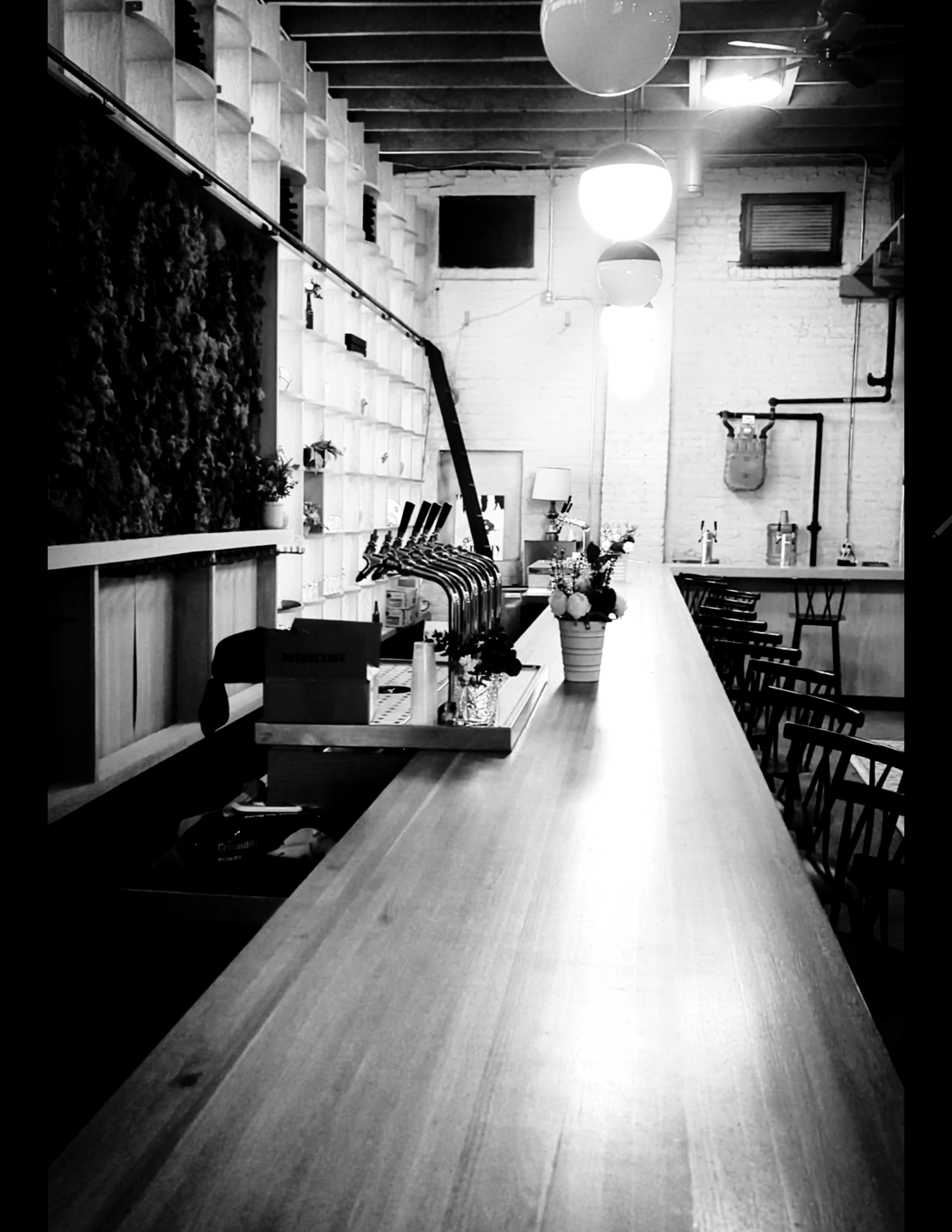 Black-and-white RISA interior with a long counter, chairs and hanging globe lights
